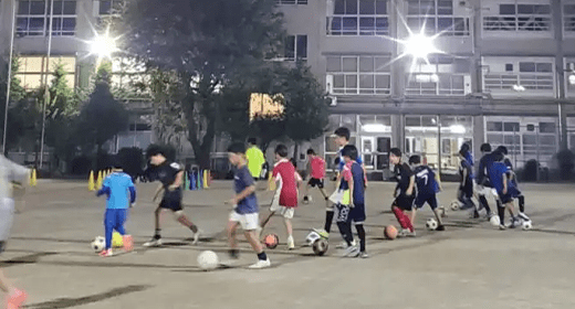ナイター照明の下でドリブル練習をする選手たち
